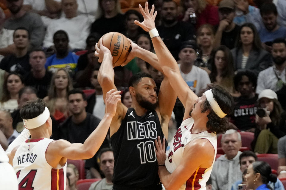 Brooklyn Nets guard Ben Simmons (10) looks for an open teammate past Miami Heat guard Tyler Herro (14) and forward Jaime Jaquez Jr. (11) during the first half of an NBA basketball game, Wednesday, Nov. 1, 2023, in Miami. (AP Photo/Wilfredo Lee)
