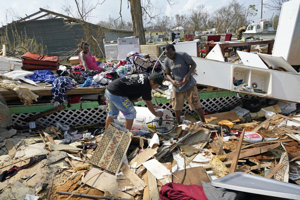 Cruz Palma, left, watches as her son, Jose Duran, center, and husband, Jose Garcia, work to remove a water heater from what's left of their home in the aftermath of Hurricane Ida, Thursday, Sept. 2, 2021, in Golden Meadow, La. (AP Photo/David J. Phillip)