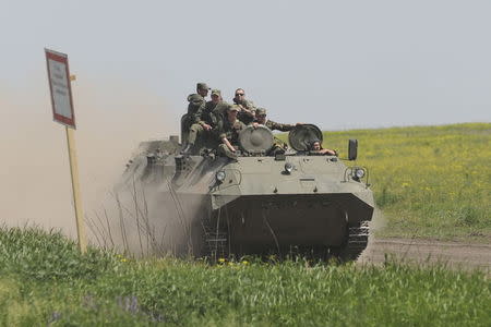 Men wearing military uniforms ride atop an armoured personnel carrier (APC) during exercises at the Kuzminsky military training ground near the Russian-Ukrainian border in Rostov region, Russia, May 25, 2015. REUTERS/Stringer