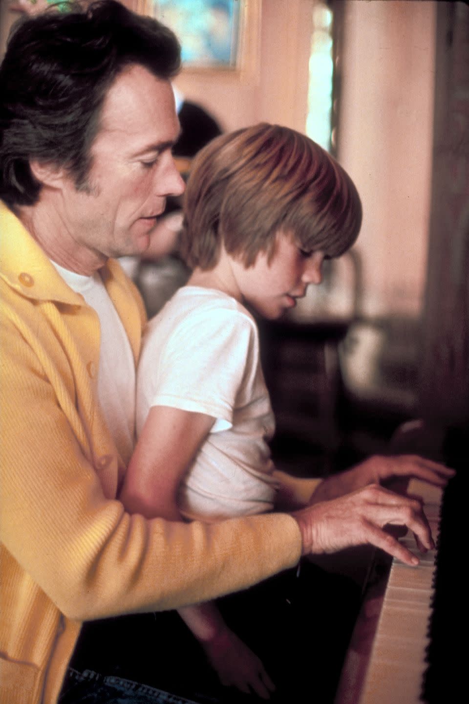 clint eastwood plays piano while kyle eastwood sits on his lap