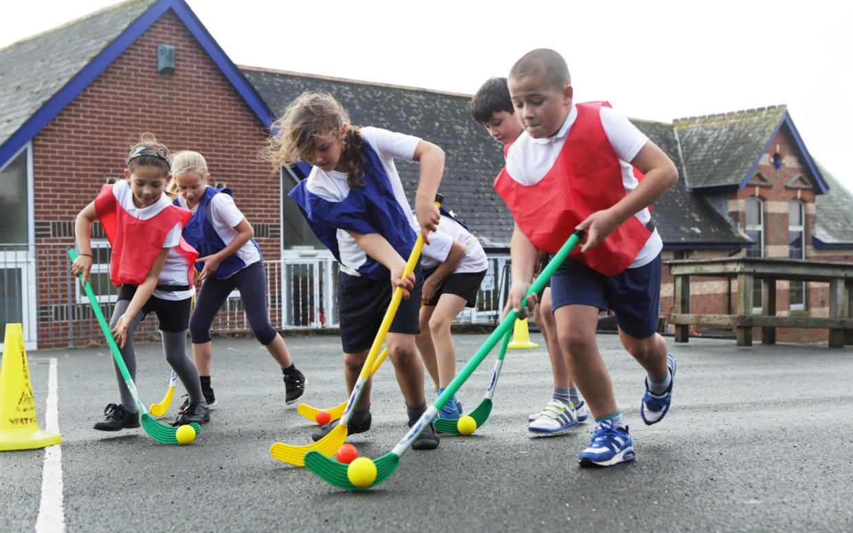 Children playing hockey in school playground