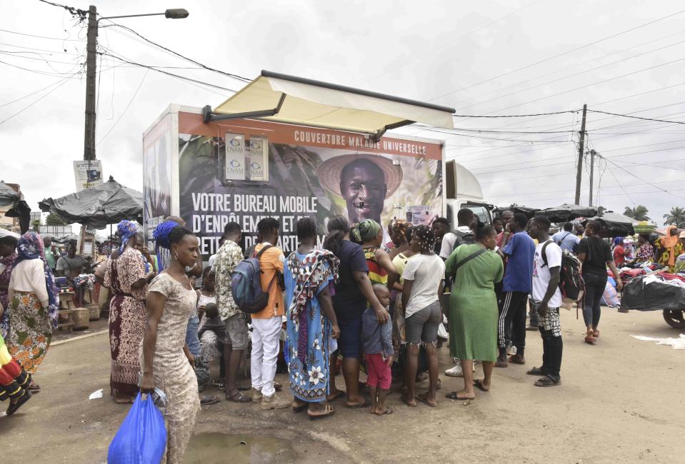 Residents line up in front of a mobile enrolment center from the Ivory Coast health authorities in Abidjan Monday, June 10, 2024. The country's universal health coverage program, has been criticized since its inception in 2019 for an inefficient voucher system that has made it impossible for participants to access the benefits. The mobile enrolment centers allow Ivorians to sign up for the scheme and provide them with cards on site, so that they can start receiving care immediately at hospitals, clinics, and pharmacies around the country. (AP Photo/ Diomande Ble Blonde)