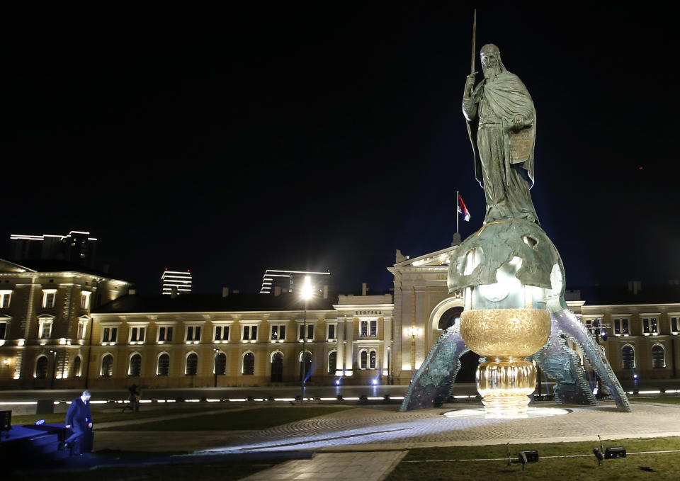 Serbian President Aleksandar Vucic walks past a 23-meter-high, 70-ton bronze sculpture of the legendary founder of the Serbian state, Stefan Nemanja, during the unveiling ceremony in Belgrade, Serbia, Wednesday, Jan. 27, 2021. President Aleksandar Vucic's allies say the bronze sculpture of Stefan Nemanja will be a new landmark of the Serbian capital. Opponents think the monument is a megalomaniac and pricy token of Vucic's populist and autocratic rule that should be removed. (AP Photo/Darko Vojinovic)