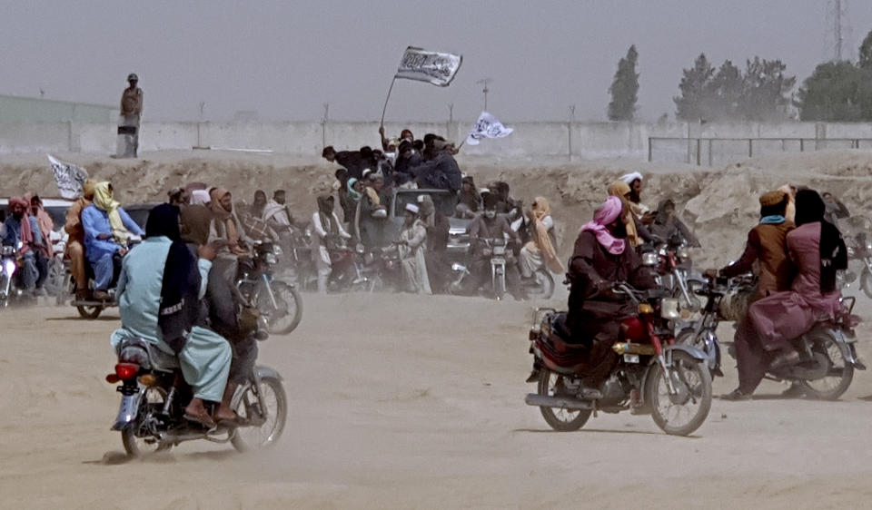 Supporters of the Taliban carry the Taliban's signature white flags in the Afghan-Pakistan border town of Chaman, Pakistan, Wednesday, July 14, 2021. The Taliban are pressing on with their surge in Afghanistan, saying Wednesday that they seized Spin Boldaka, a strategic border crossing with Pakistan — the latest in a series of key border post to come under their control in recent weeks. (AP Photo/Tariq Achkzai)