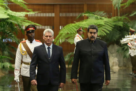 Cuban President Miguel Diaz-Canel (L) and Venezuela's President Nicolas Maduro review an honour guard during a ceremony at the Revolution Palace in Havana, Cuba April 21, 2018. REUTERS/Alexandre Meneghini