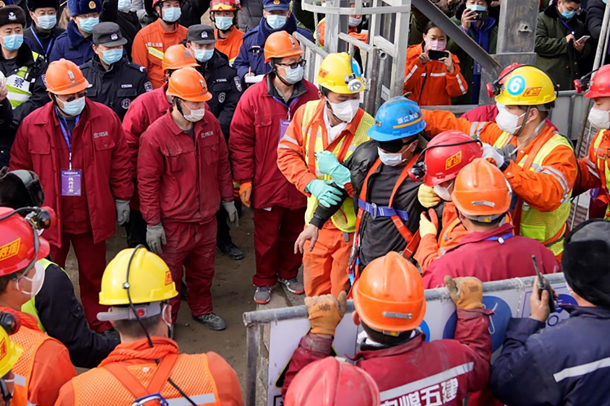 <p>One (blue helmet) of the 22 miners rescued from hundreds of metres underground in a gold mine in China </p> (CNS/AFP via Getty Images)