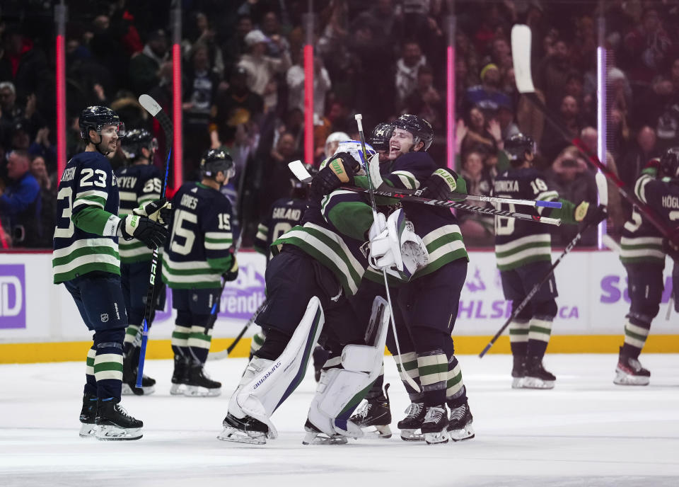 Vancouver Canucks' Riley Stillman, right, Ethan Bear, back, and goalie Spencer Martin celebrate after the Canucks defeated the Arizona Coyotes during overtime in an NHL hockey game Saturday, Dec. 3, 2022, in Vancouver, British Columbia. (Darryl Dyck/The Canadian Press via AP)