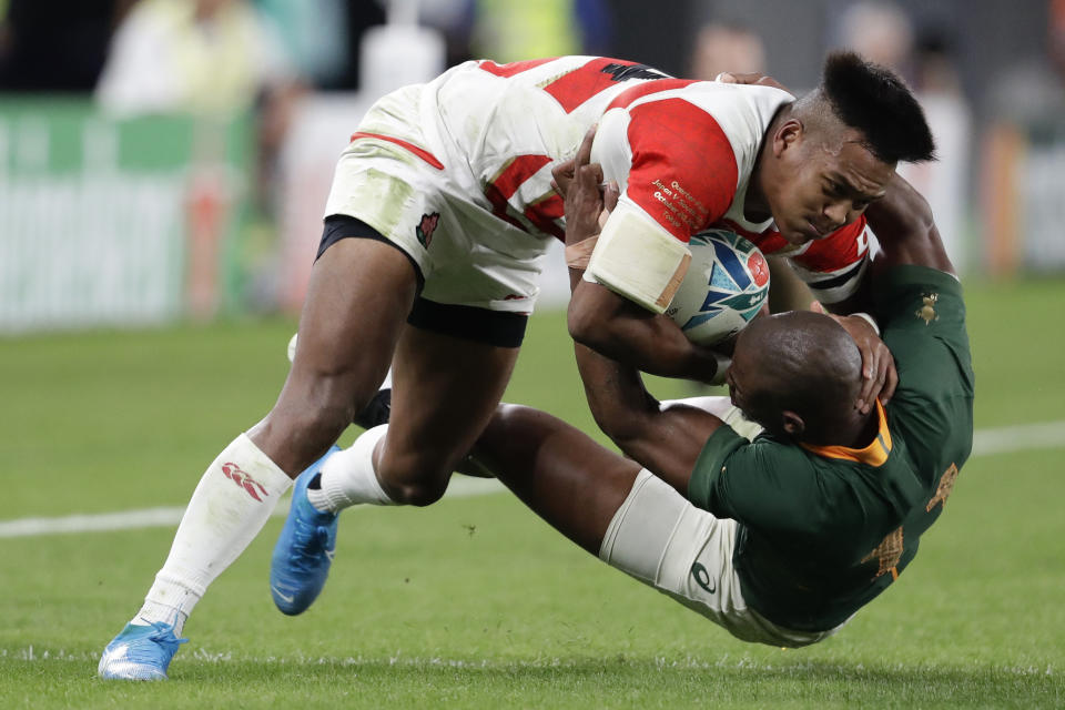South Africa's Makazole Mapimpi tackles Japan's Kotaro Matsushima during the Rugby World Cup quarterfinal match at Tokyo Stadium between Japan and South Africa in Tokyo, Japan, Sunday, Oct. 20, 2019. (AP Photo/Mark Baker)