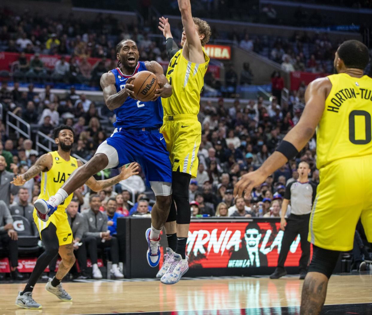 Clippers forward Kawhi Leonard drives to the hoop under pressure from Utah Jazz forward Lauri Markkanen.