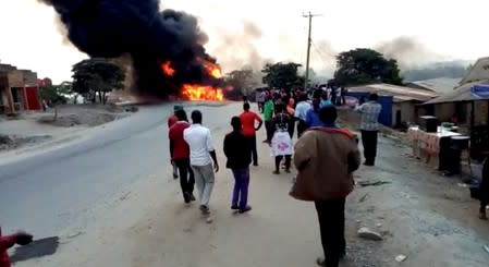 People look towards a fire following a fuel truck collision in Rubirizi