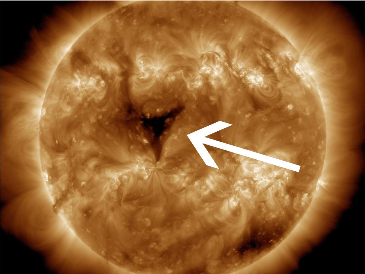 A picture of the sun zoomed in with an arrow pointing to a giant black hole on it's surface