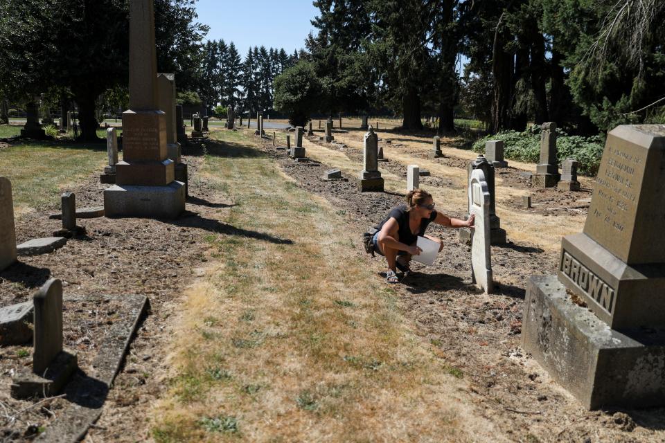 Heather Lagaso of Gervais cleans a headstone at Belle Passi Cemetery.