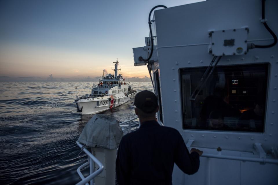 A member of the Philippine Coast Guard looks out at a China Coast Guard ship in the disputed South China Sea, in November 2023. (Photo: Lisa Marie David/Bloomberg)