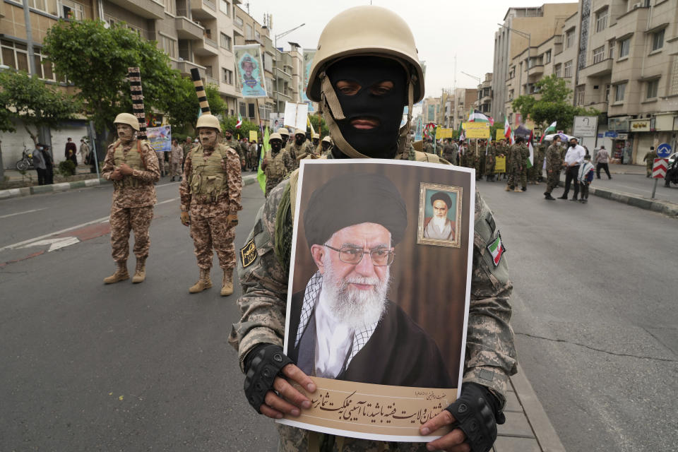 A Basij paramilitary force member holds a poster showing Supreme Leader Ayatollah Khamenei and late revolutionary founder Ayatollah Khomeini, top right, during the annual pro-Palestinian Al-Quds, or Jerusalem, Day rally in Tehran, Iran, Friday, April 29, 2022. Iran does not recognize Israel and supports Hamas and Hezbollah, militant groups that oppose it. Signs on head bands show support Iranian supreme leader Ayatollah Ali Khamenei. (AP Photo/Vahid Salemi)