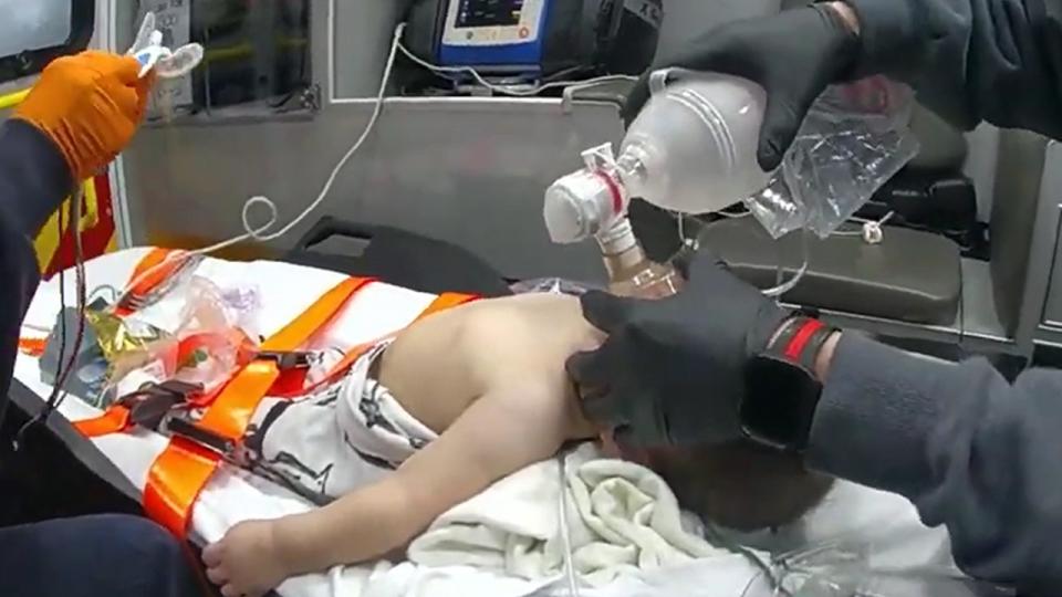 EMT holds breathing device over infant's mouth and nostrils