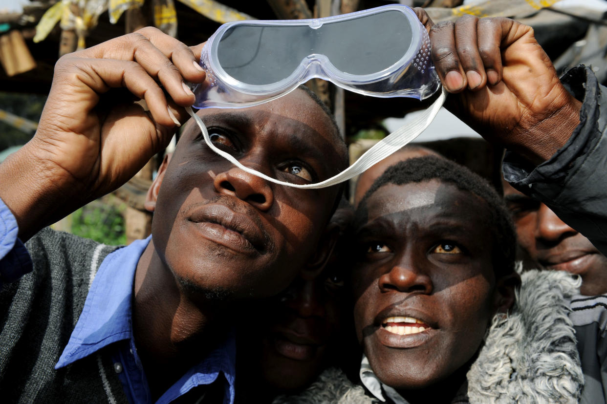 2010: Residents of a village in Nairobi, Kenya, share a pair of dark goggles as they look at a solar eclipse. 