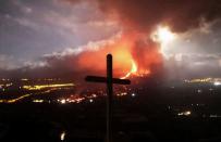 FILE PHOTO: A cross is seen as lava and smoke rise following the eruption of a volcano on the Island of La Palma