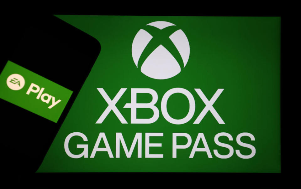 Screen displaying Xbox Game Pass logo and an EA Play logo on a smartphone against a green background