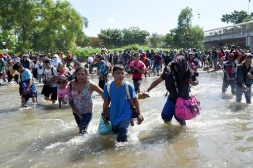 Central American migrants -- mostly Hondurans travelling in a caravan to the US -- cross the Suichate River between Guatemala and Mexico, where Mexican forces fired tear gas trying to force them back