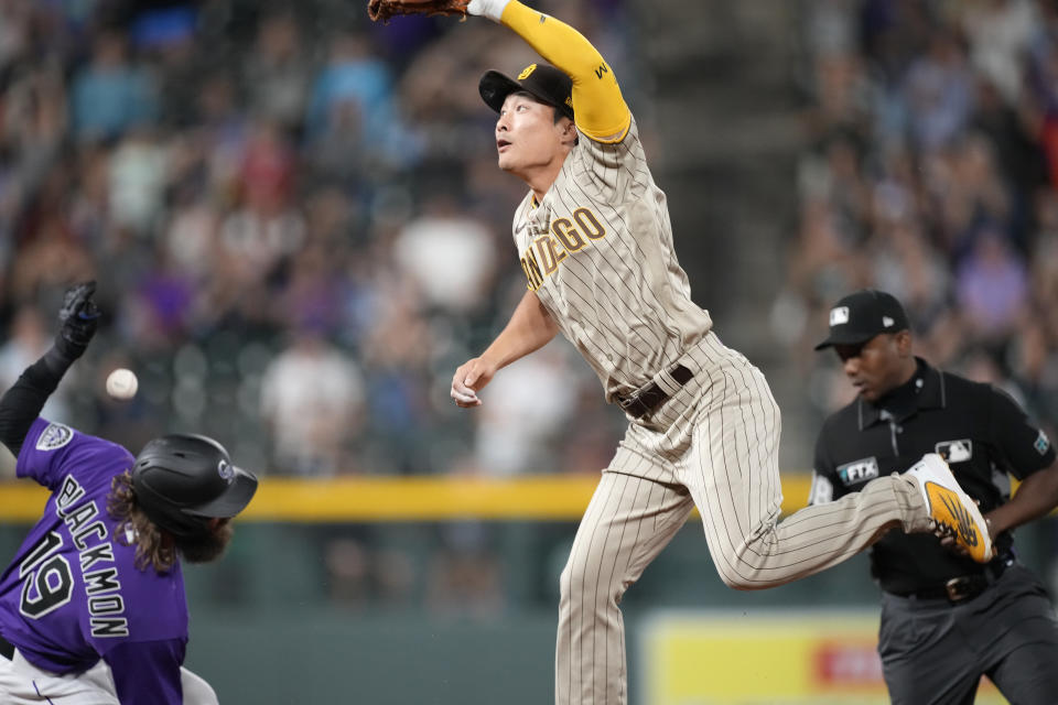 San Diego Padres shortstop Ha-Seong Kim, center, tries to field the throw as Colorado Rockies' Charlie Blackmon, left, slides safely into second base with an RBI-double in the ninth inning of a baseball game Monday, July 11, 2022, in Denver. (AP Photo/David Zalubowski)