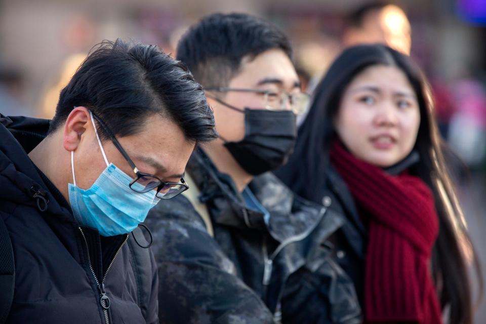 Travelers wear face masks as they walk outside of the Beijing Railway Station in Beijing, Monday, Jan. 20, 2020. China reported Monday a sharp rise in the number of people infected with a new coronavirus, including the first cases in the capital. The outbreak coincides with the country's busiest travel period, as millions board trains and planes for the Lunar New Year holidays. (AP Photo/Mark Schiefelbein)