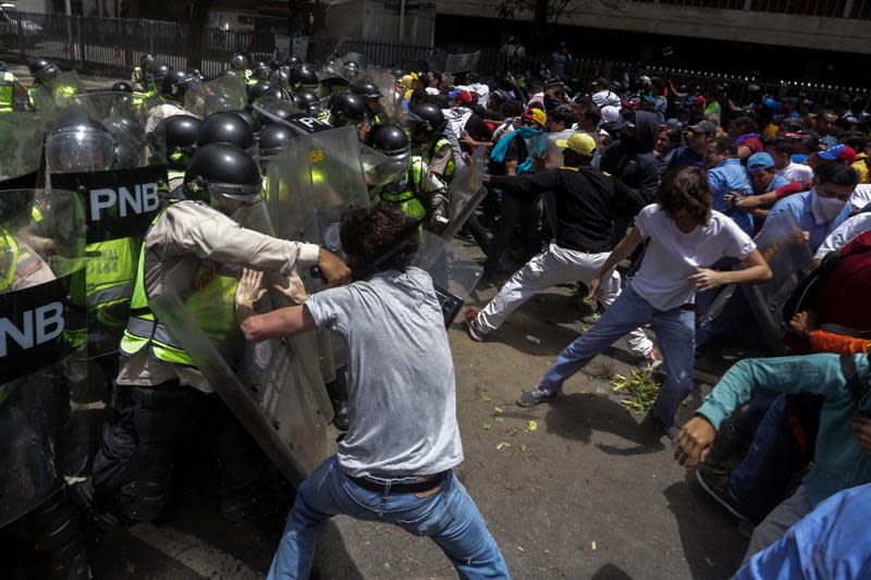 <p>Opositores al gobierno del presidente venezolano Nicolás Maduro se enfrentan a miembros de la Guardia Nacional Bolivariana de Venezuela durante una manifestación hoy, martes 4 de abril de 2017, que intentaba marchar hacia el Parlamento en apoyo a la destitución de los magistrados del Supremo, en Caracas (Venezuela). La Guardia Nacional Bolivariana de Venezuela (GNB, policía militar) disolvió hoy con gases lacrimógenos y perdigones de goma una manifestación de decenas de opositores. EFE/CRISTIAN HERNÁNDE </p>