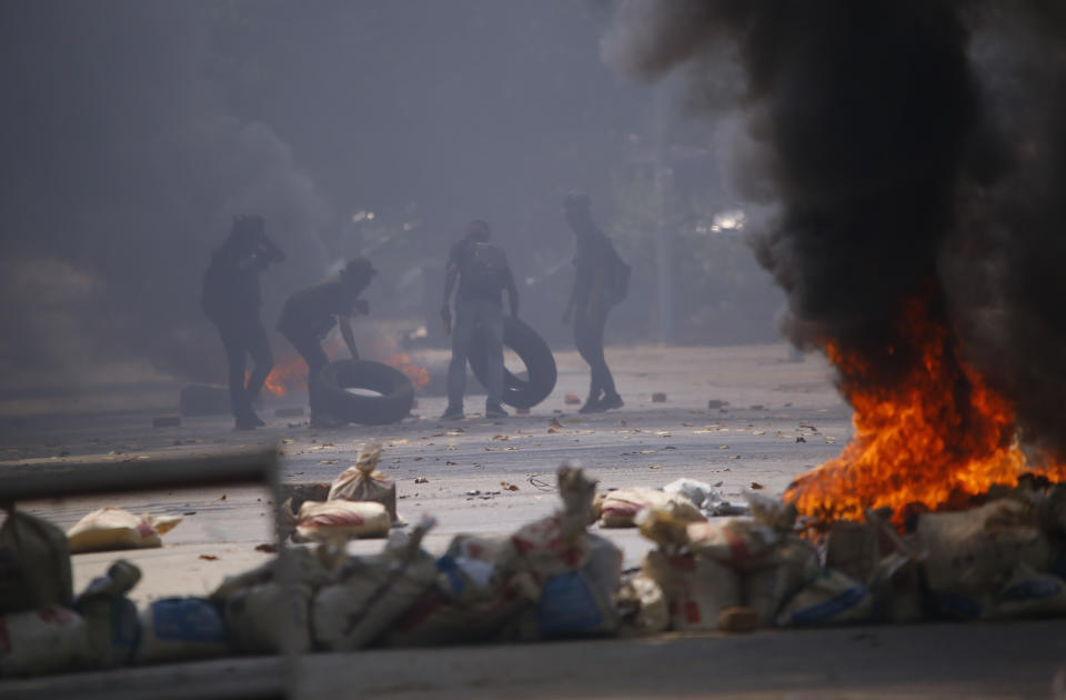 Manifestantes amontonan neumáticos para lanzarlos a las llamas durante un acto contra el golpe militar, sábado 27 de marzo de 2021, en el municipio de Tarmwe en Yangon, Myanmar. (AP Foto)