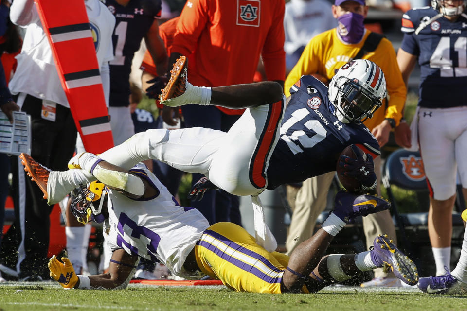 Auburn wide receiver Eli Stove (12) is tacked by LSU linebacker Micah Baskerville (23) as he reaches for the first down marker during the second quarter of an NCAA college football game Saturday, Oct. 31, 2020, in Auburn, Ala. (AP Photo/Butch Dill)