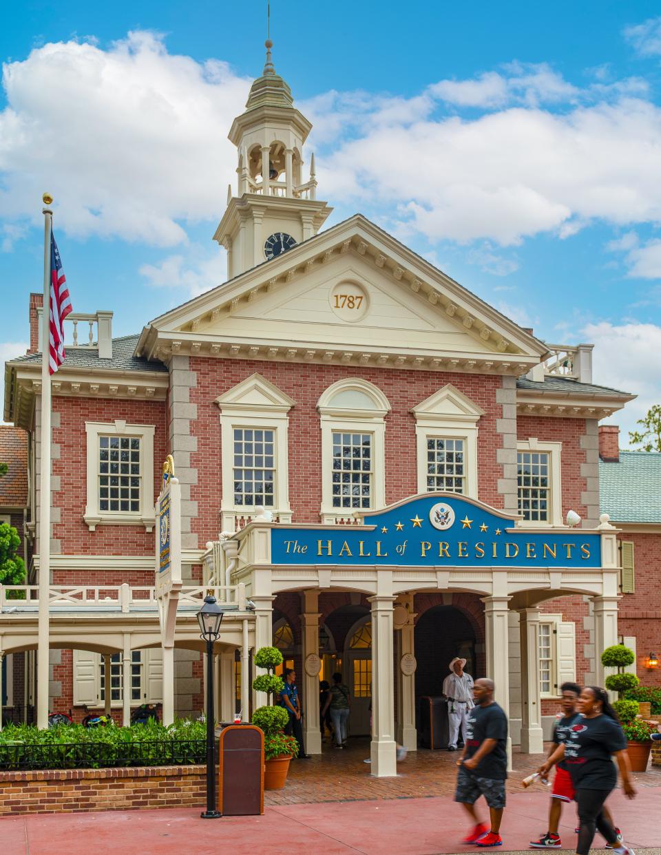 Tourists walking in front of the Hall of the Presidents at Walt Disney World's Magic Kingdom amusement park.