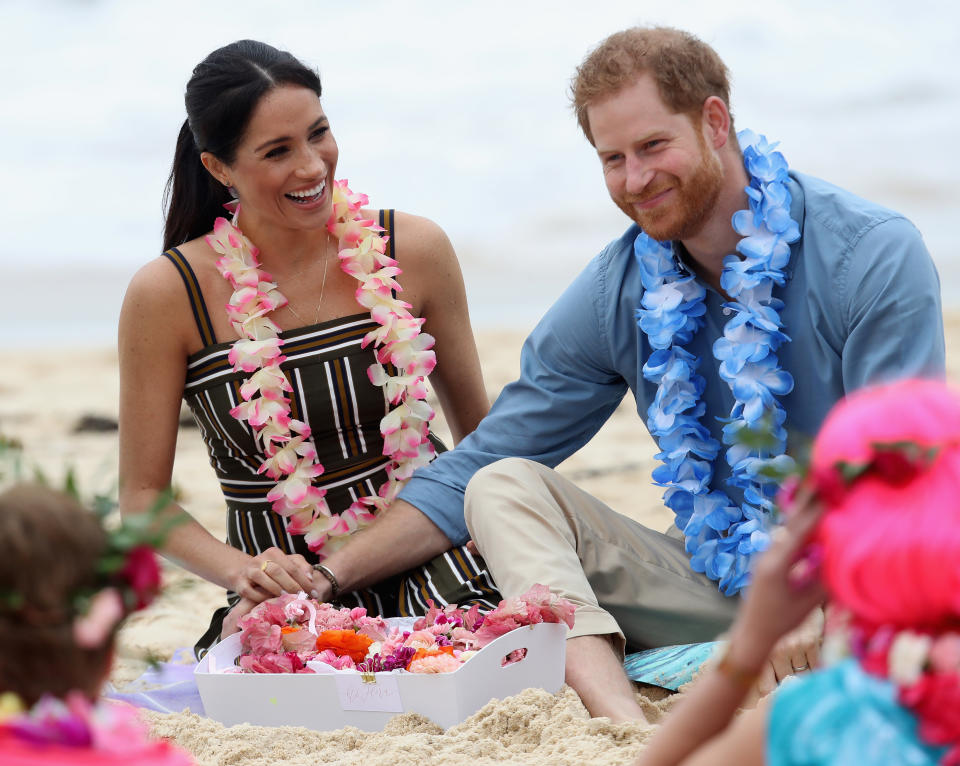 Prince Harry and Meghan Markle wear leis while on the beach