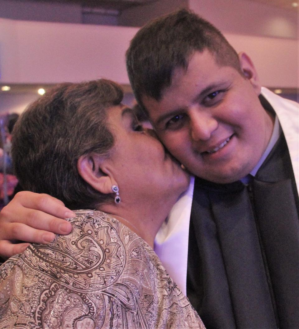 Margarita Aguirre gives her grandson Luis Mancha a kiss - un beso - after Texas Leadership Charter Academy graduation.