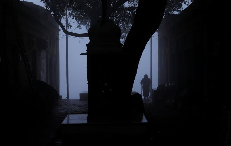 A woman stands on the banks of the Yamuna river on a foggy winter morning in New Delhi