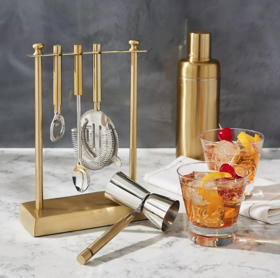 Gold bar tool set next to two cocktails and golden shaker in back