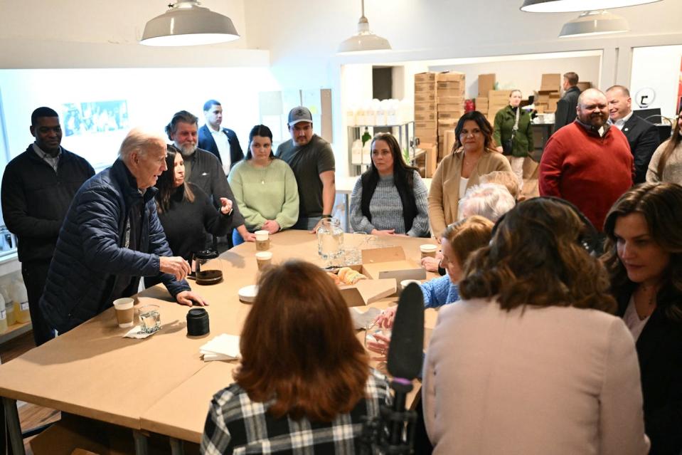 A man standing at a table talking to about a dozen people around the table.