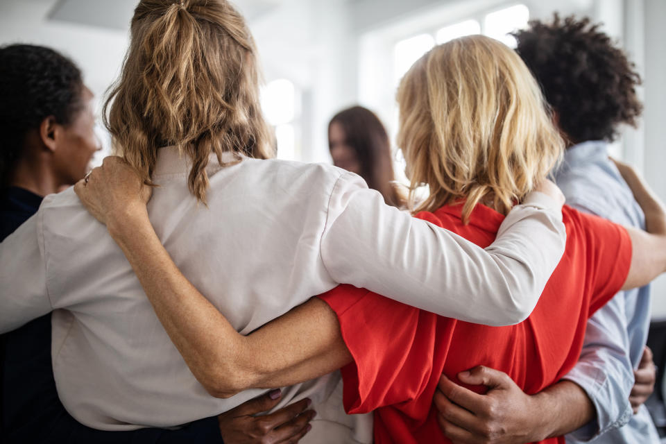 Group of diverse people in a circle with their arms around each other in a supportive gesture