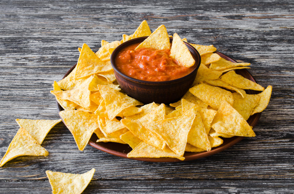 Nachos corn chips with spicy tomato sauce. Mexican food concept. Yellow corn totopos chips with salsa sauce. Top view.