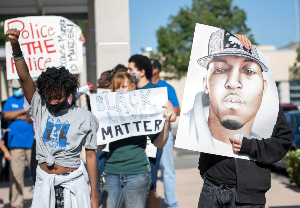 A woman raises her fist next to a person holding a portrait of Malcolm Harsch during a protest over the death of Harsch, a black man who was found hanging from a tree on June 16 in Victorville, Calif. (Valerie Macon/AFP via Getty Images)