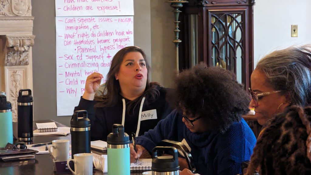 A woman at a table speaking.