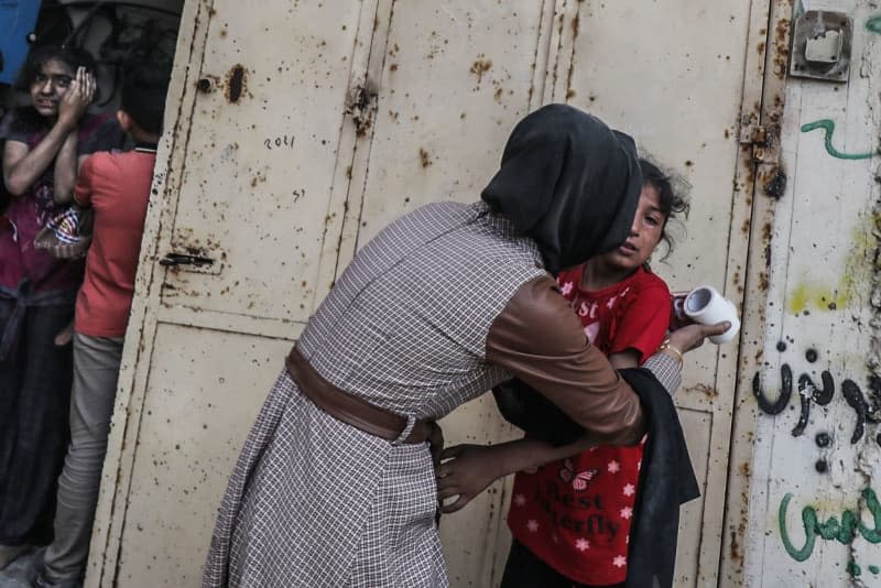 A Palestinian woman comforts a young girl after the Israeli bombing of a populated residential building in Nuseirat. Omar Naaman/dpa