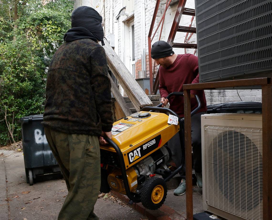 Brothers Tom and Derek Markey carry a portable generator outside of Betsy’s Crepes restaurant on Monday, Dec. 5, 2022, in Southern Pines, N.C. Tom Markey, an employee at the business, said the generator was purchased a few years ago for power outages due to severe weather, but this is its first use. Kaitlin McKeown/kmckeown@newsobserver.com