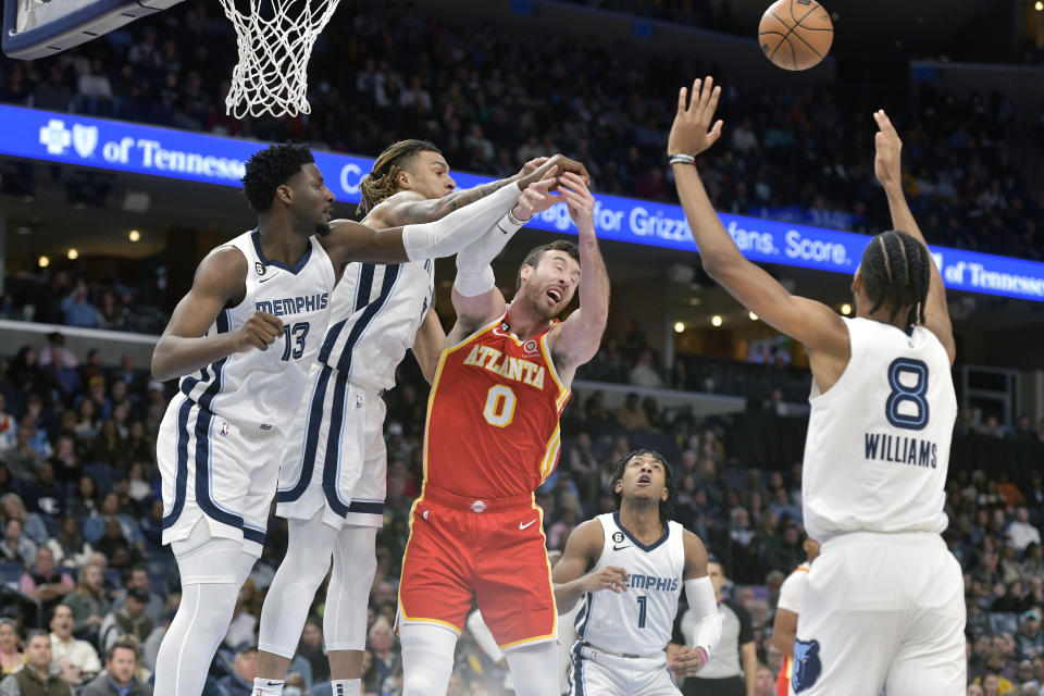 Atlanta Hawks forward Frank Kaminsky (0) struggles for control of the ball against Memphis Grizzlies forwards Jaren Jackson Jr. (13) and Brandon Clarke, second from left, in the first half of an NBA basketball game Monday, Dec. 12, 2022, in Memphis, Tenn. (AP Photo/Brandon Dill)