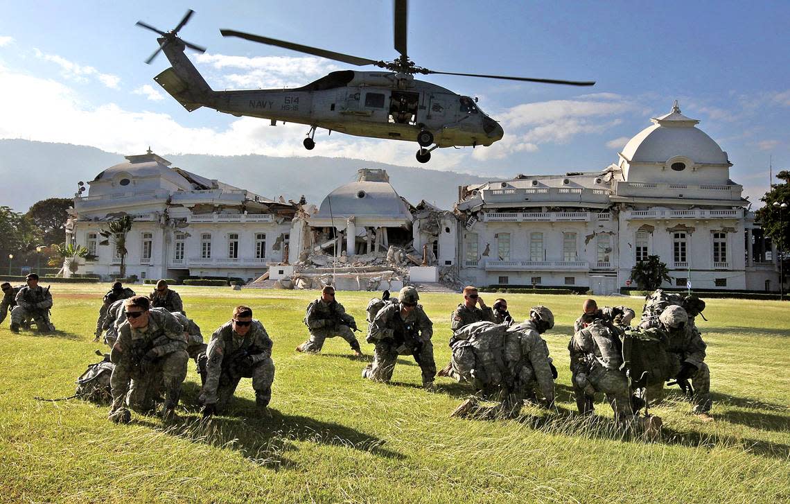 Soldiers avoid rotor wash as a Navy helicopter lifts off after the earthquake in Haiti.