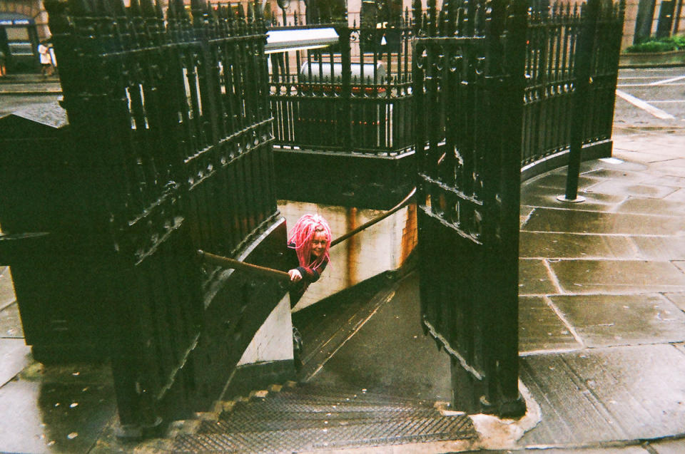 A pink-haired woman peeks round a corner. (Cafe Art/SWNS)