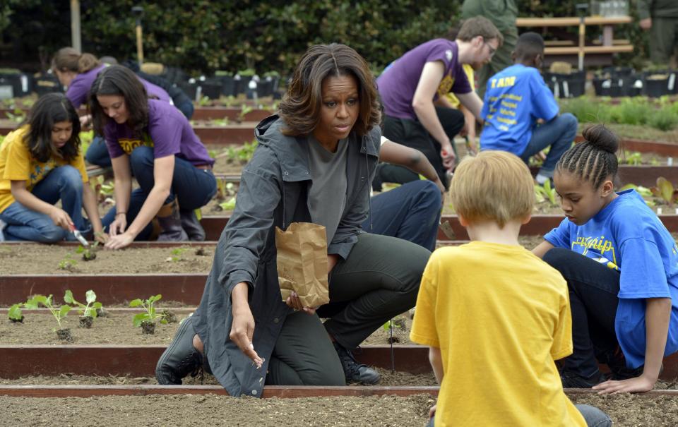 First lady Michelle Obama talks with Friendship Public Charter Elementary School student Dynasty Meade, right, and Bancroft Elementary School student Silas Stutz, second from right in yellow, as they plant Lincoln oats in the White House Kitchen Garden at the White House in Washington, Wednesday, April 2, 2014. (AP Photo/Susan Walsh)