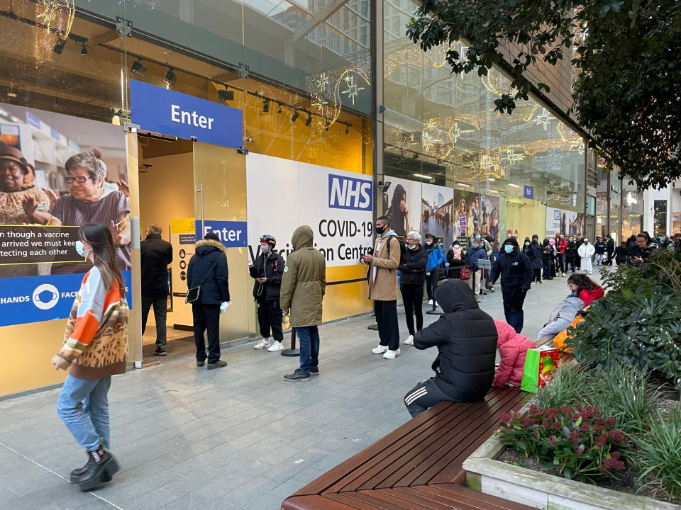 People queue at a COVID Vaccination Centre at the Westfield shopping centre in Stratford, east London, as the coronavirus booster vaccination programme continues across the UK. Despite the ramping-up of the booster programme, experts said it would not help in terms of hospitals admissions in the near future, as many would be people who are infected now before immunity has had time to build. Picture date: Monday December 20, 2021. (Photo by Jonathan Brady/PA Images via Getty Images)