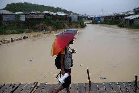 A volunteer of Bangladesh Red Crescent Society Bangladesh walks in the rain to call for the Rohingya refugees who have missing relatives in Myanmar or other countries, in Kutupalong camp in Cox's Bazar, Bangladesh July 4, 2018. Picture taken July 4, 2018. REUTERS/Mohammad Ponir Hossain