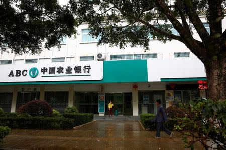 A man walks past a branch of the Agricultural Bank of China in the town of Nansan, Yunnan province, China, March 12, 2017. REUTERS/Thomas Peter