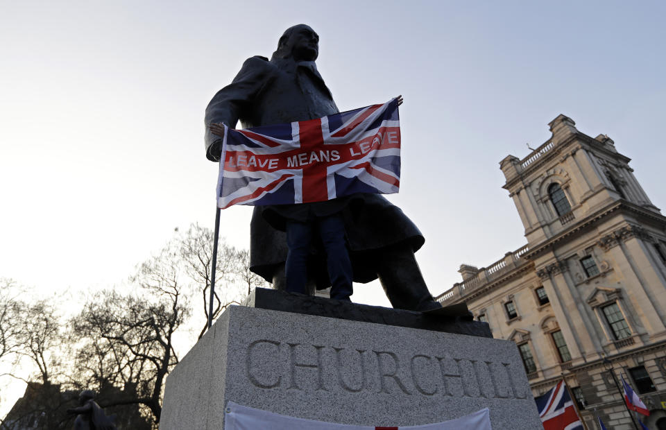 FILE - In this file photo dated Friday, March 29, 2019, a pro-Brexit demonstrator holds a British flag with the words "Leave Means Leave" in front of the Winston Churchill statue in London. The Brexit decision to split from the European Union was fuelled by a sense that the U.K. is fundamentally separate from its continental neighbours, but both sides of the Brexit debate conjure up strong historical concepts for this sceptered isle.(AP Photo/ Kirsty Wigglesworth, FILE)