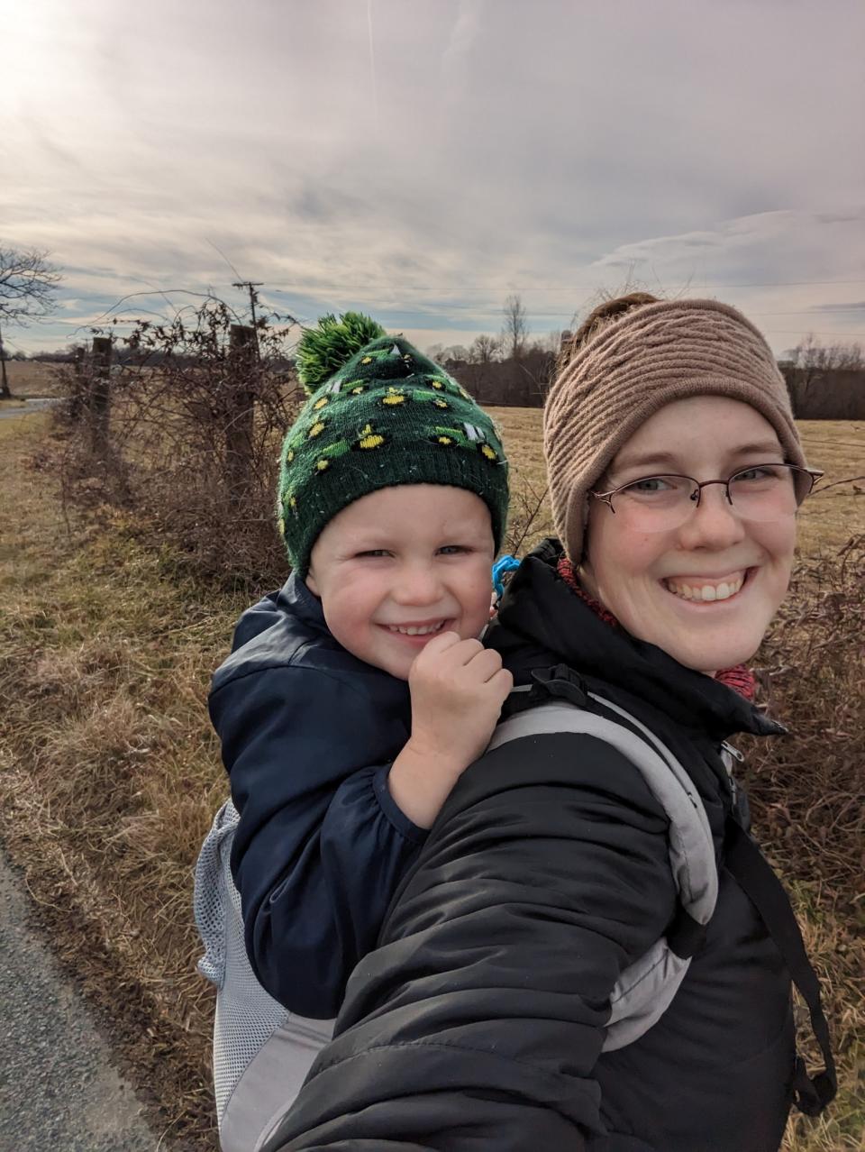 Susanna Vaughan and her son Erik on her back outdoors.