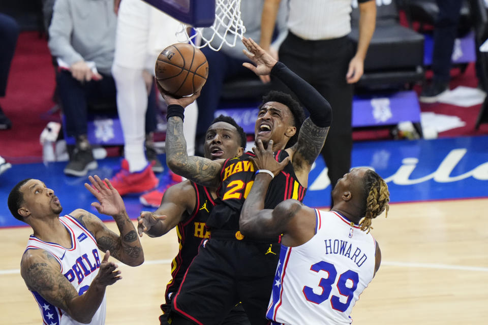 Atlanta Hawks' John Collins, center, is fouled by Philadelphia 76ers' Dwight Howard, right, during the second half of Game 7 in a second-round NBA basketball playoff series, Sunday, June 20, 2021, in Philadelphia. (AP Photo/Matt Slocum)